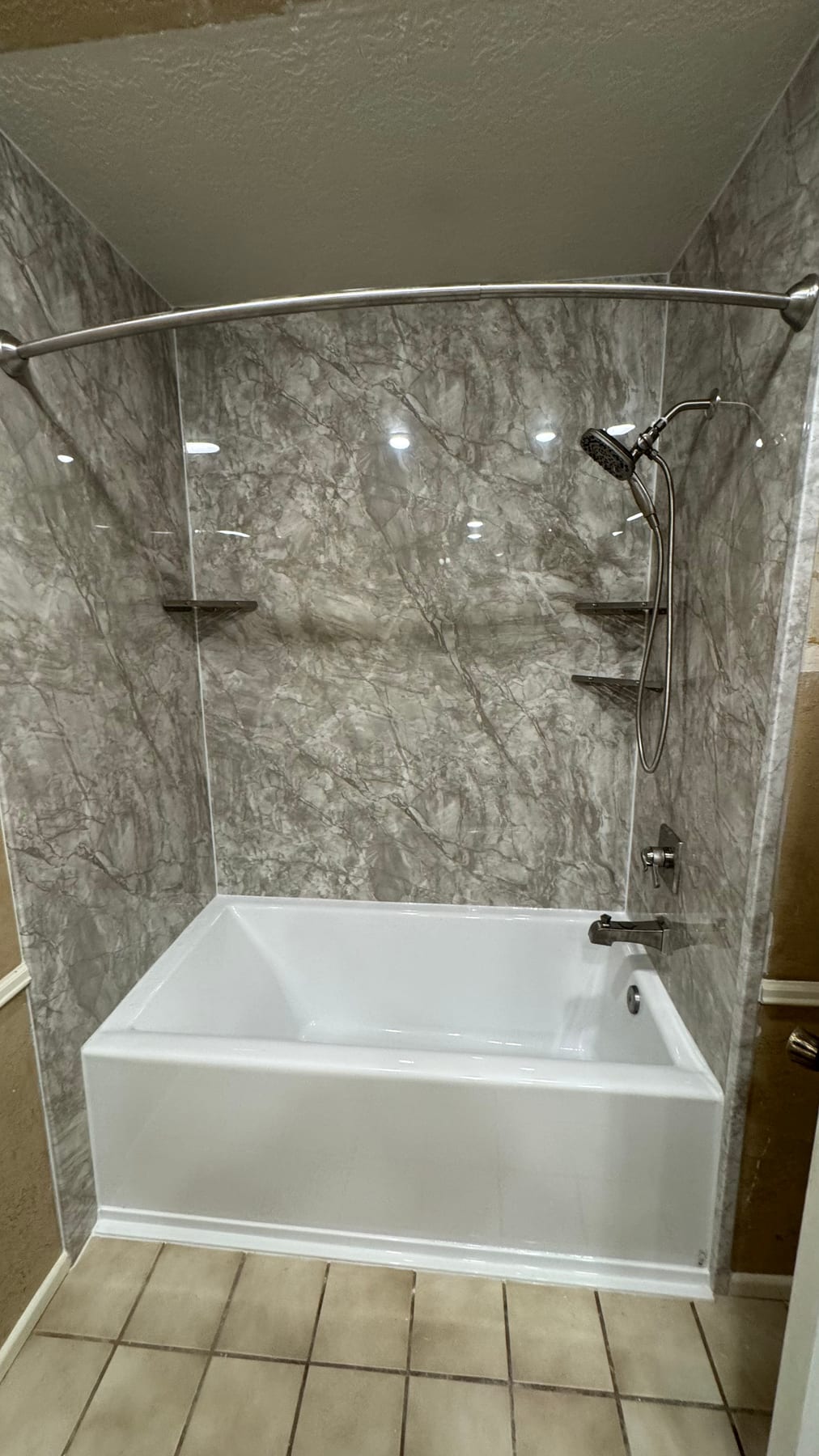 Gray stone-look tub and shower surround with built-in shelves