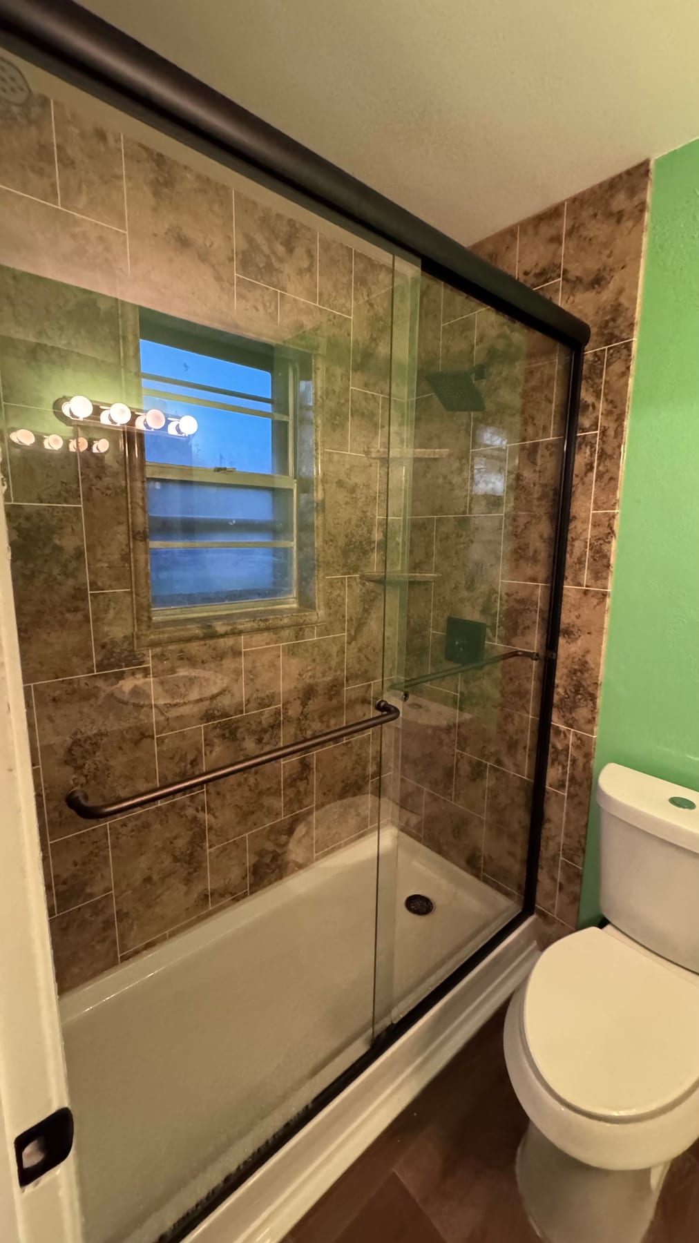 Tile shower upgraded with a black-framed glass enclosure