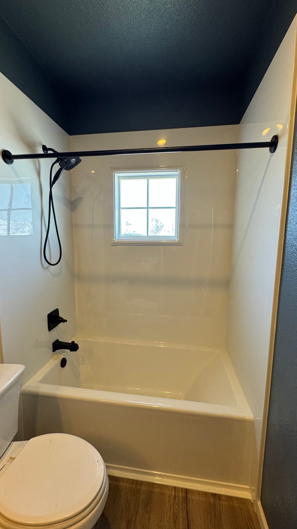White tub and shower surround with matte-black fixtures